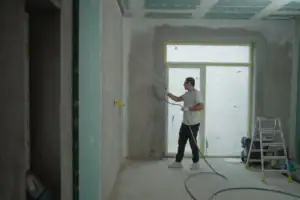man applies paint to a room using a spray gun