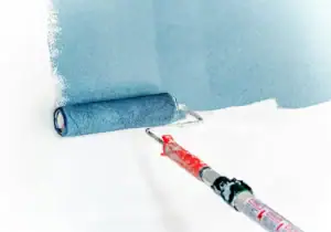A roller is being used to coat a wall with paint.