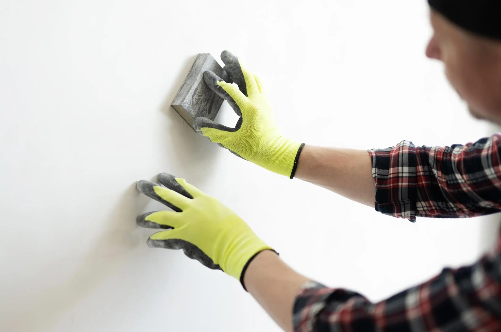 professional painter sanding and preparing wall surface before applying paint